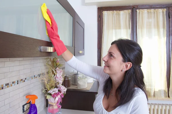 Красивая молодая домохозяйка чистит мебель на кухне — стоковое фото