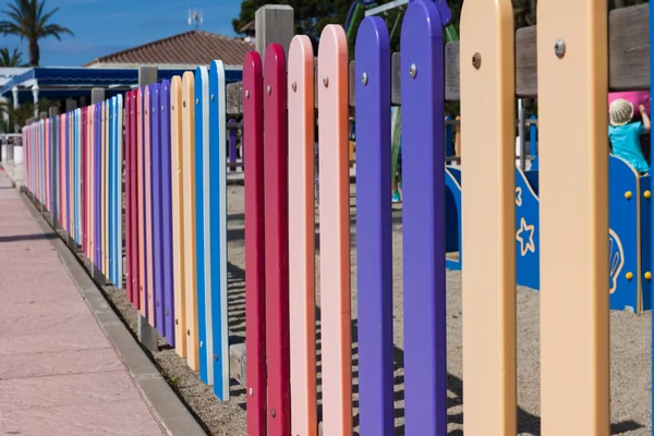 Warna-warni baris kayu dicat di pagar taman bermain — Stok Foto