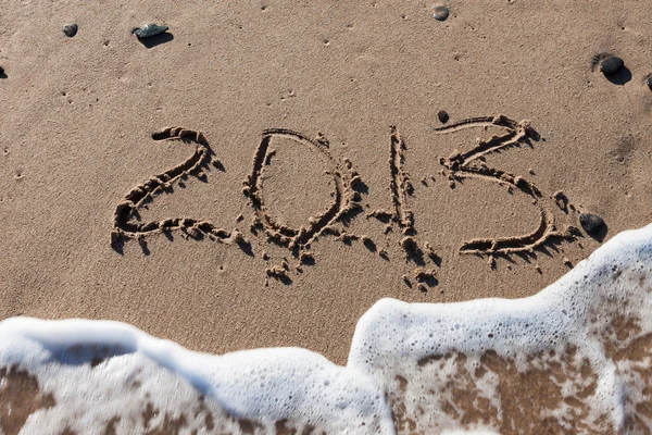 Числа 2013 на морском песке с волновой водой — стоковое фото