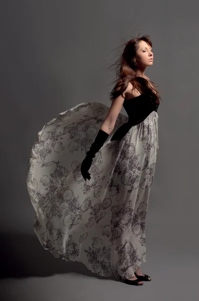 stock image Young girl in evening dress. On a gray background.