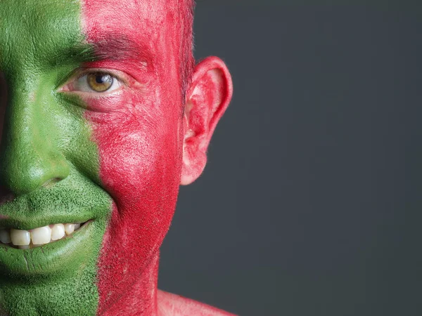 Mann lächelt und sein Gesicht mit der Flagge Portugals bemalt. — Stockfoto
