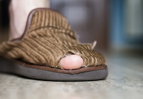 Broken slipper with hole and finger — Stock Photo, Image