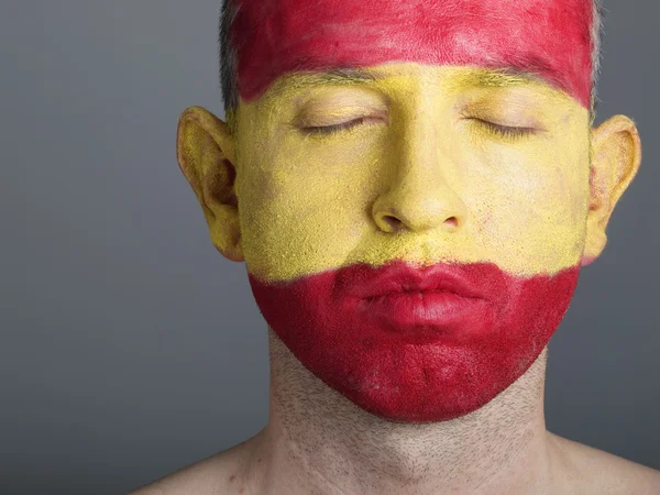 Männergesicht bemalt mit der Flagge Spaniens, geschlossene Augen. — Stockfoto