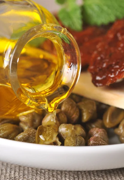 Сушеные помидоры, каперсы и оливковое масло на тарелке — стоковое фото