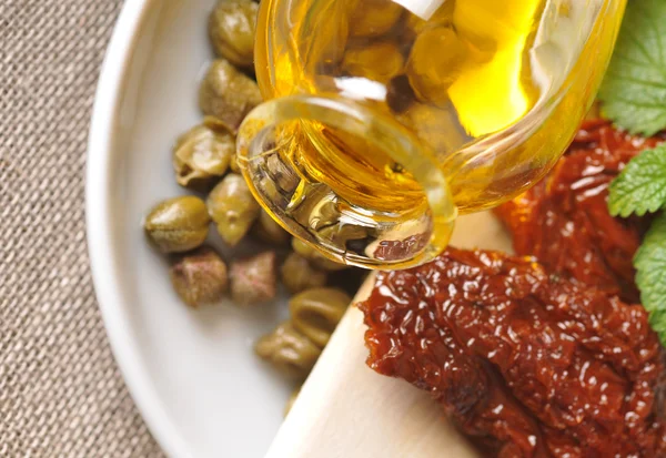 Tomates secos, alcaparras y aceite de oliva en el plato —  Fotos de Stock