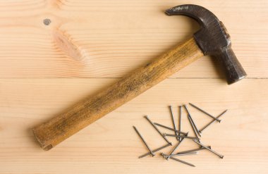 Old hammer and iron nails on wooden floor clipart