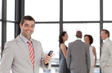 Hispanic businessman holding a phone at workplace with his colle clipart