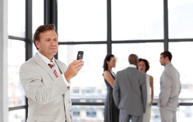 Caucasian businessman holding a phone at workplace with his coll clipart