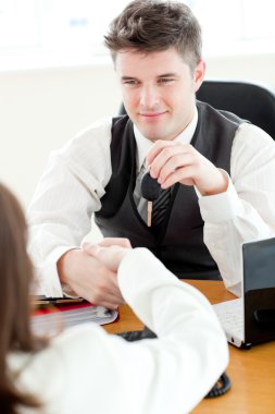 Young attractive salesman giving car's key to his customer clipart