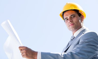 Smiling male architect holding a blueprint clipart