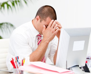 Frustrated businessman working at a computer clipart