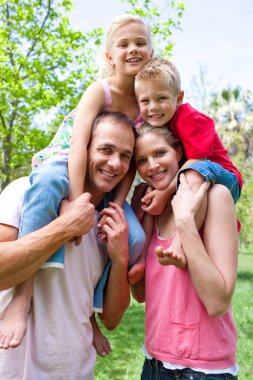 Happy parents giving their children piggy-back ride clipart