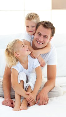 Caring father with his children sitting on bed clipart