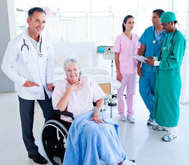 Positive medical team taking care of a senior woman clipart