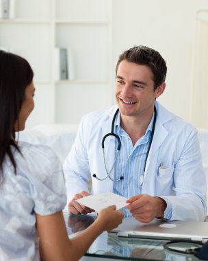 Smiling doctor giving a prescription to his female patient clipart