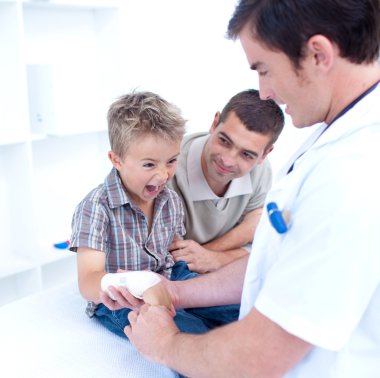 Doctor bandagins a child's arm who is yelling clipart