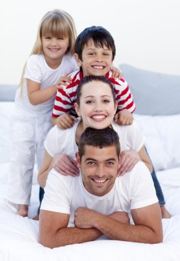 Happy family playing in bed together clipart