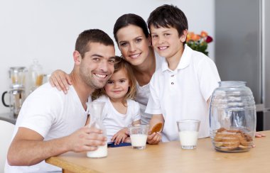 Happy family eating biscuits and drinking milk clipart