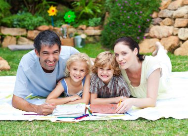 Happy family painting in a park smiling at the camera clipart