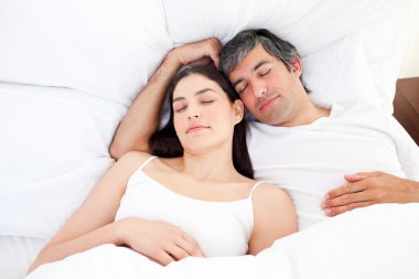 Affectionate couple hugging lying in their bed clipart