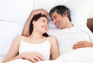 Enamored couple hugging lying in their bed clipart