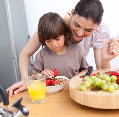 Jolly mother and her child having breakfast clipart