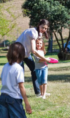 Happy mother playing frisbee with her children clipart