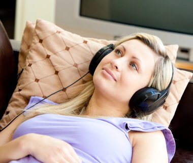 Cheerful woman is listening the music in the living-room at homewoman clipart