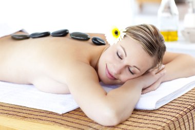 Happy young woman with hot stone on her back and closed eyes clipart