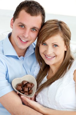 Hugging couple holding chocolote smiling at the camera clipart