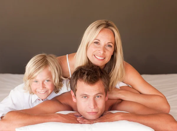 Gülümseyen aile birlikte eğleniyor yatakta yatarken — Stok fotoğraf