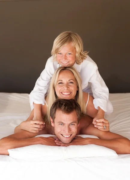 Familia feliz divirtiéndose juntos acostados en la cama —  Fotos de Stock