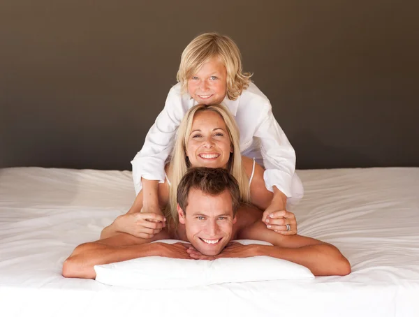 Милая семья веселится вместе лежа на кровати — стоковое фото