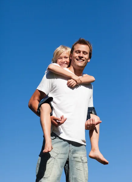 Sorrindo pai com seu filho em suas costas ao ar livre — Fotografia de Stock
