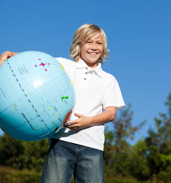 Молодой парень держит глобус на открытом воздухе — стоковое фото