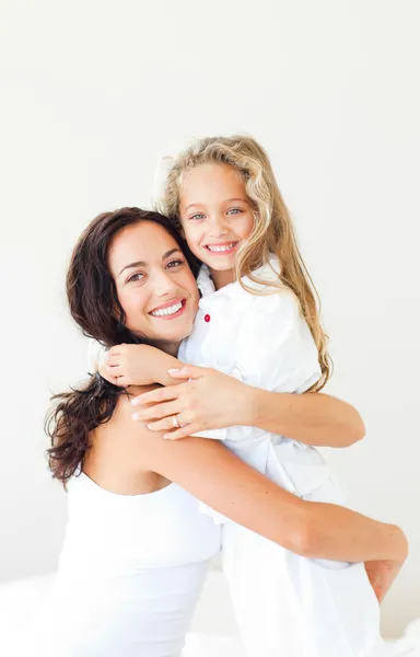 Delighted mother and daughter on a white bed — Stock Photo, Image