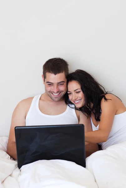 Glimlachend paar ontspannen op hun bed thuis — Stockfoto