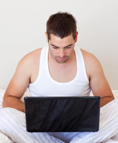 Yakışıklı bir adam üstünde laptop evde çalışma — Stok fotoğraf