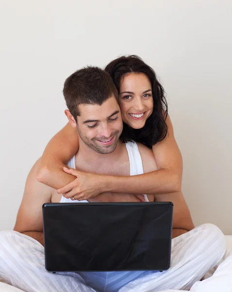 Casal romântico usando um laptop deitado — Fotografia de Stock