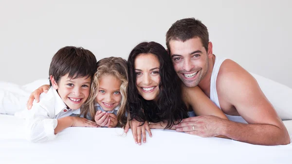 Cheerful family lying on a bed — Stock Photo, Image
