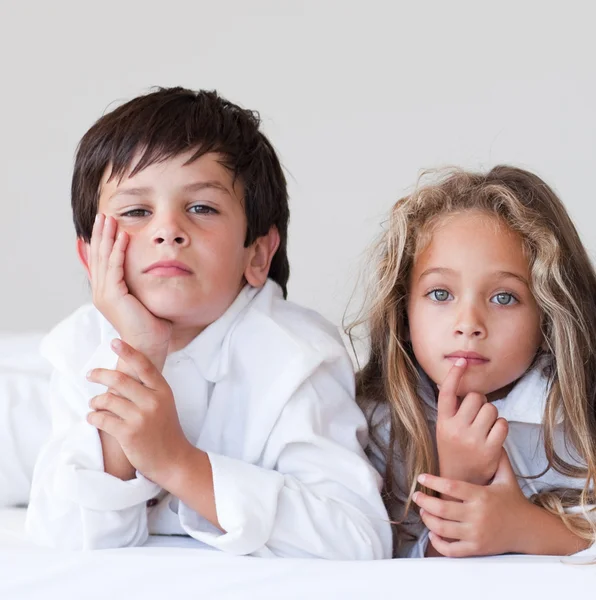 Unhappy boy lying on the bed with his sister — Stock Photo, Image