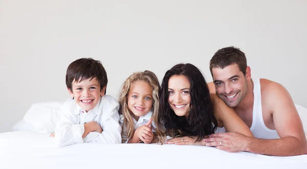 Glödande familj ligger på sängen — Stockfoto