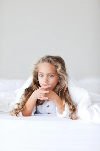 Blondes Mädchen liegt auf einem weißen Bett — Stockfoto