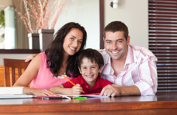 Usměvavá mladá familie sedící u stolu — Stock fotografie