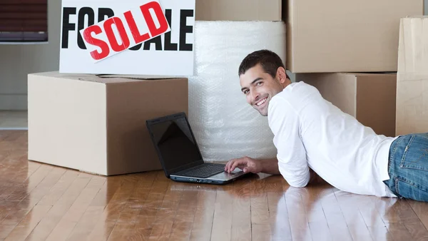 Sorrindo homem em sua nova casa com seu laptop — Fotografia de Stock