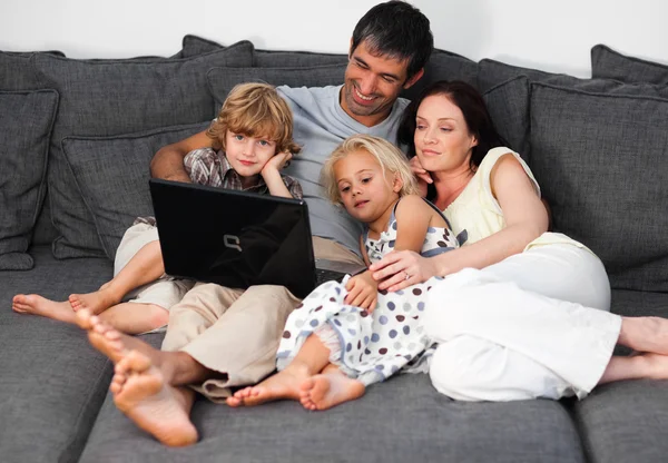 Νεαρή οικογένεια σε έναν καναπέ με ένα laptop — Φωτογραφία Αρχείου