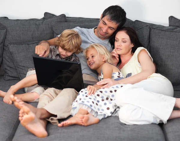Jeune famille assise sur le canapé — Photo