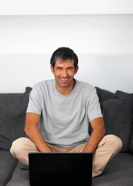 Przystojny mężczyzna siedzi na kanapie z laptopem — Zdjęcie stockowe