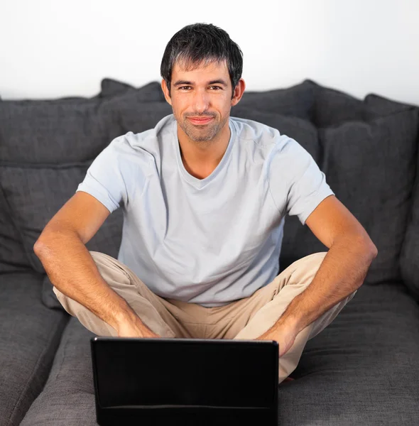 Uśmiechnięty mężczyzna z laptopa w salonie — Zdjęcie stockowe
