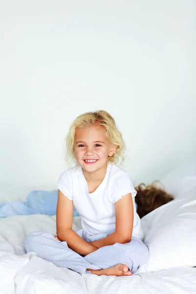 Meisje met broer op het bed — Stockfoto